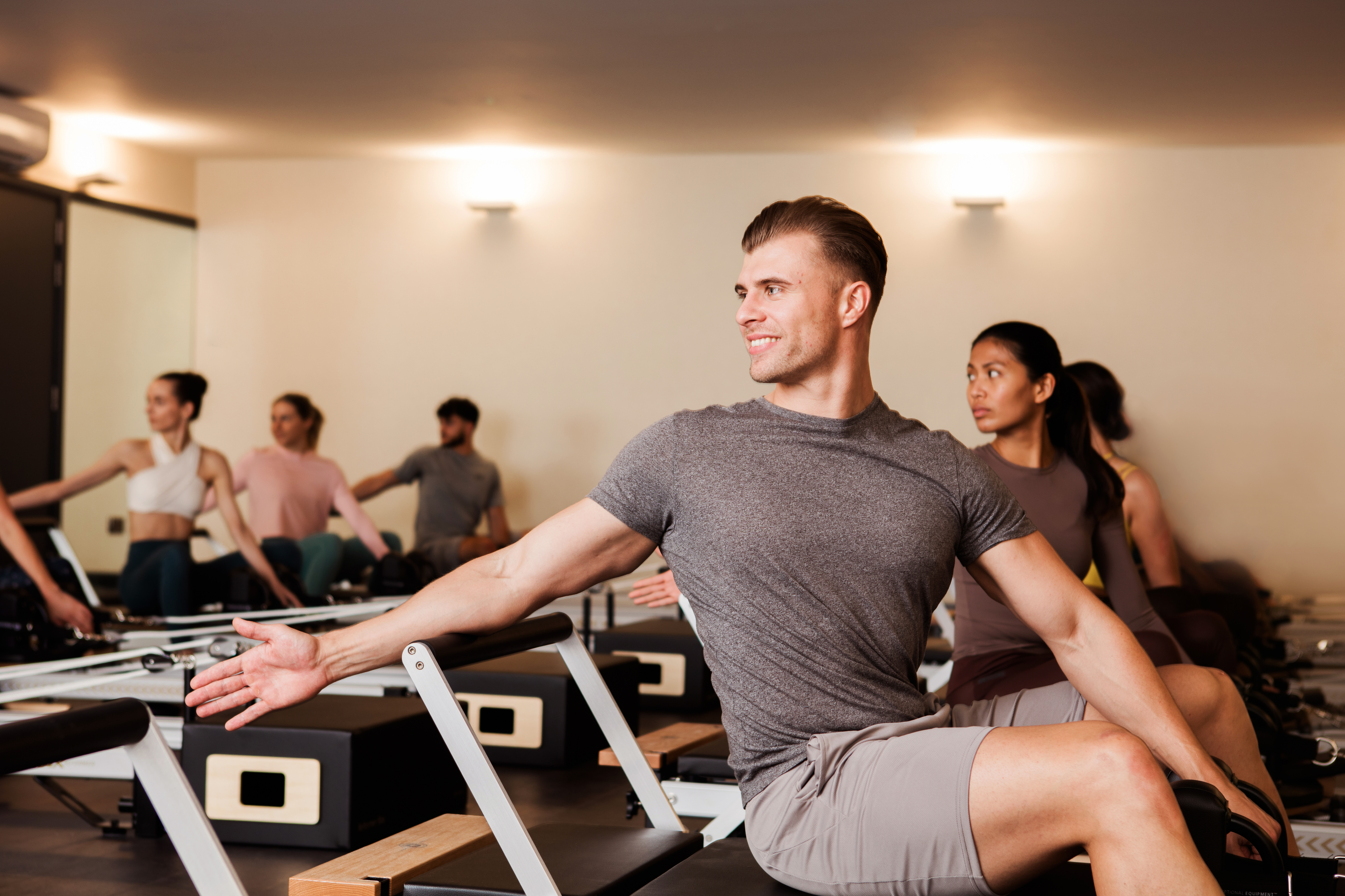 Man at the front of a Reformer Pilates class